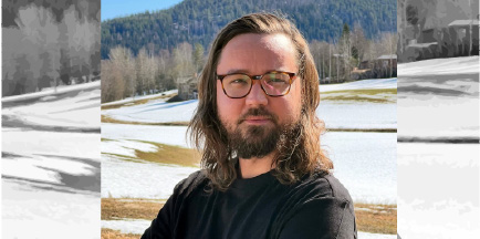 Joakim Karsberg står i naturen med glasögon på sig.